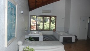 A modern bathroom with a large window, a bathtub, a sink, and a shower area. - Australis Paradise (Carilo)