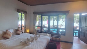 Habitación de hotel con una cama grande, un banco de madera y vista al área de la piscina.