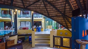 Un espacio interior con techo alto, zona de piscina y bar.
