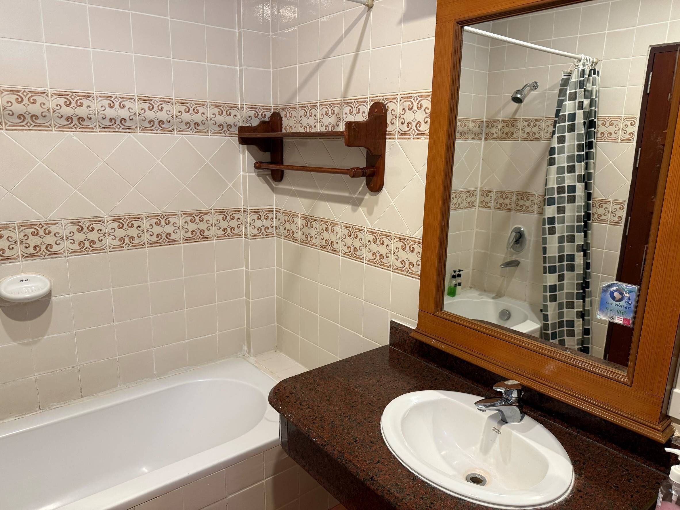 A bathroom with a white bathtub, a sink with a mirror above it, and a shower curtain.