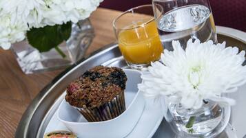A tray with a muffin, a glass of orange juice, a glass of water, and a small container of jam.