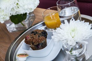 A tray with a muffin, a glass of orange juice, a glass of water, and a small container of jam.