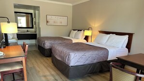 A hotel room with two beds, a desk, a chair, a lamp, and a painting on the wall.