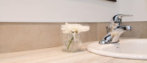A bathroom with a white sink, a chrome faucet, and a large mirror with a black frame.
