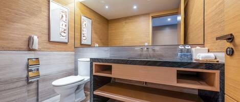 A modern bathroom with a marble vanity, wooden cabinetry, and a large mirror.