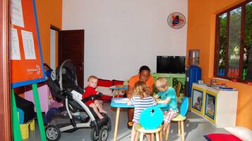 A playroom with a play table, chairs, a stroller, and a water dispenser.