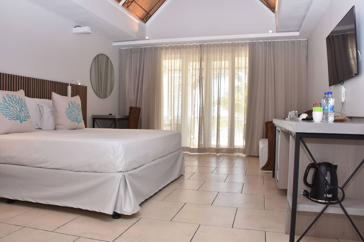 Habitación de hotel con cama, escritorio, televisor y ventana con cortinas.