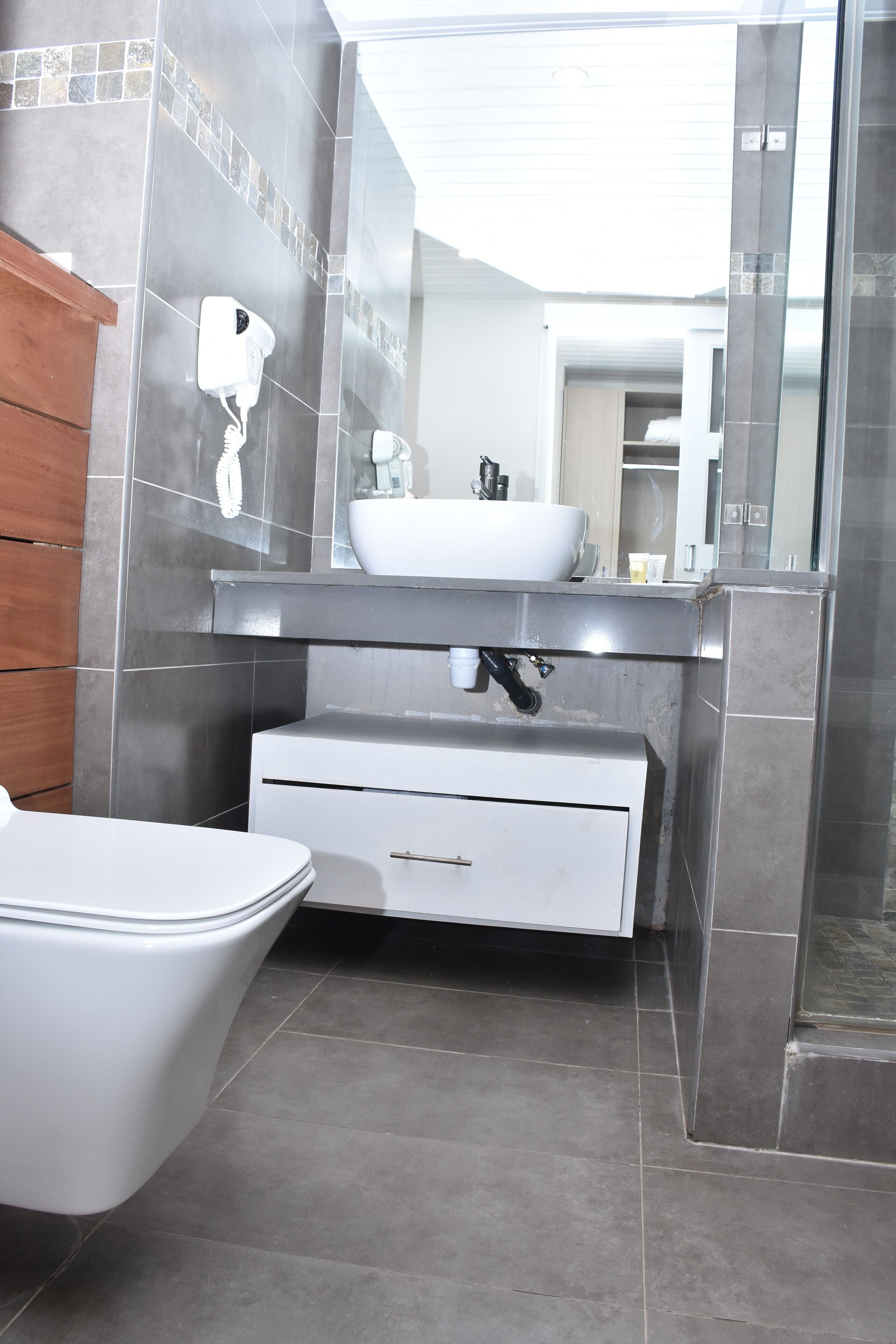 A modern bathroom with a white toilet, a sink with a mirror above, and a shower area.