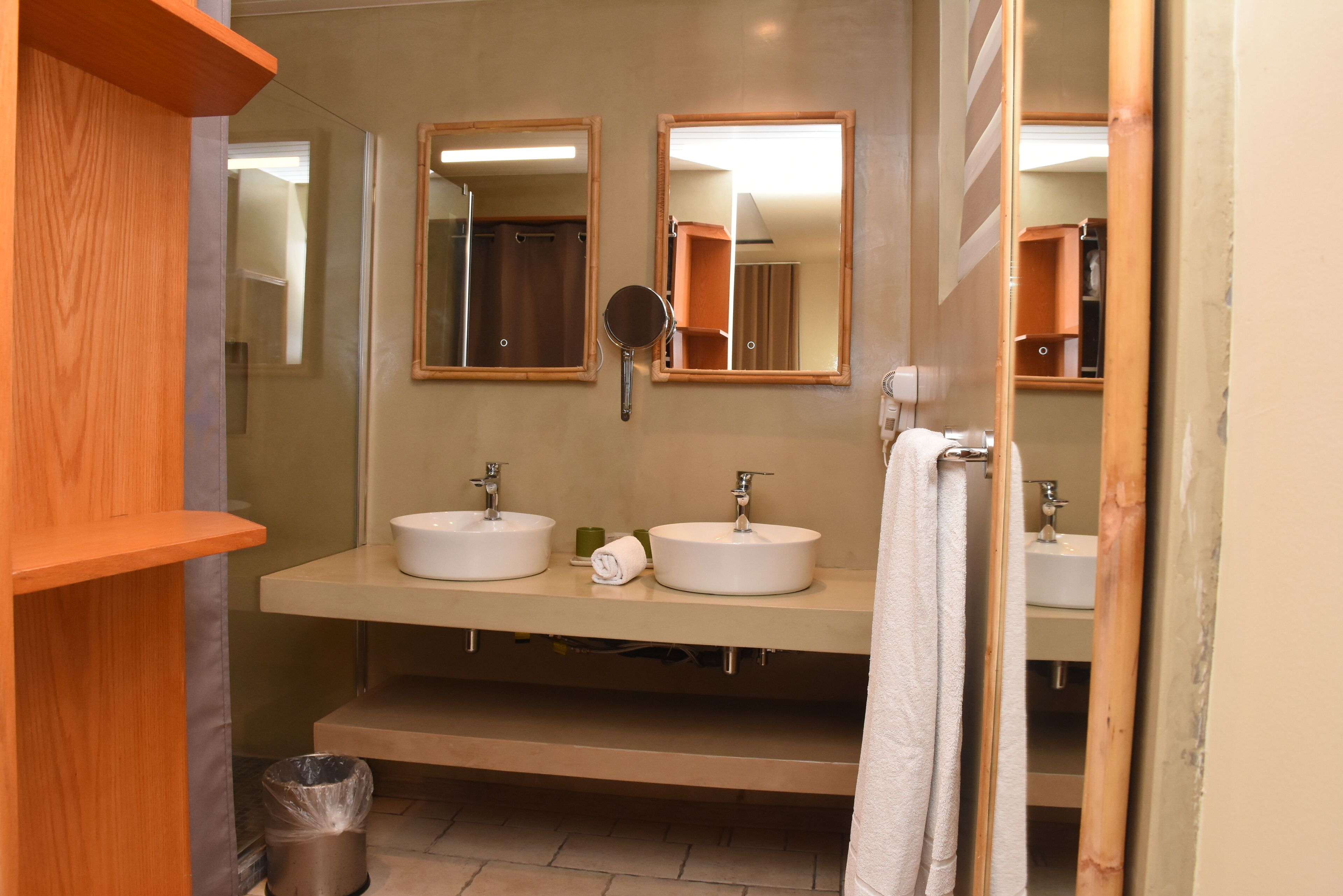 A bathroom with two sinks, a mirror, and a trash bin.