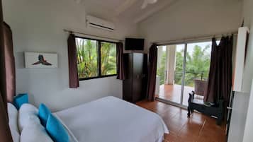A bedroom with a bed, a TV, and a balcony with a chair.