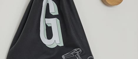 Un sac noir orné d’un grand « G » et d’une illustration représentant un sèche-cheveux.