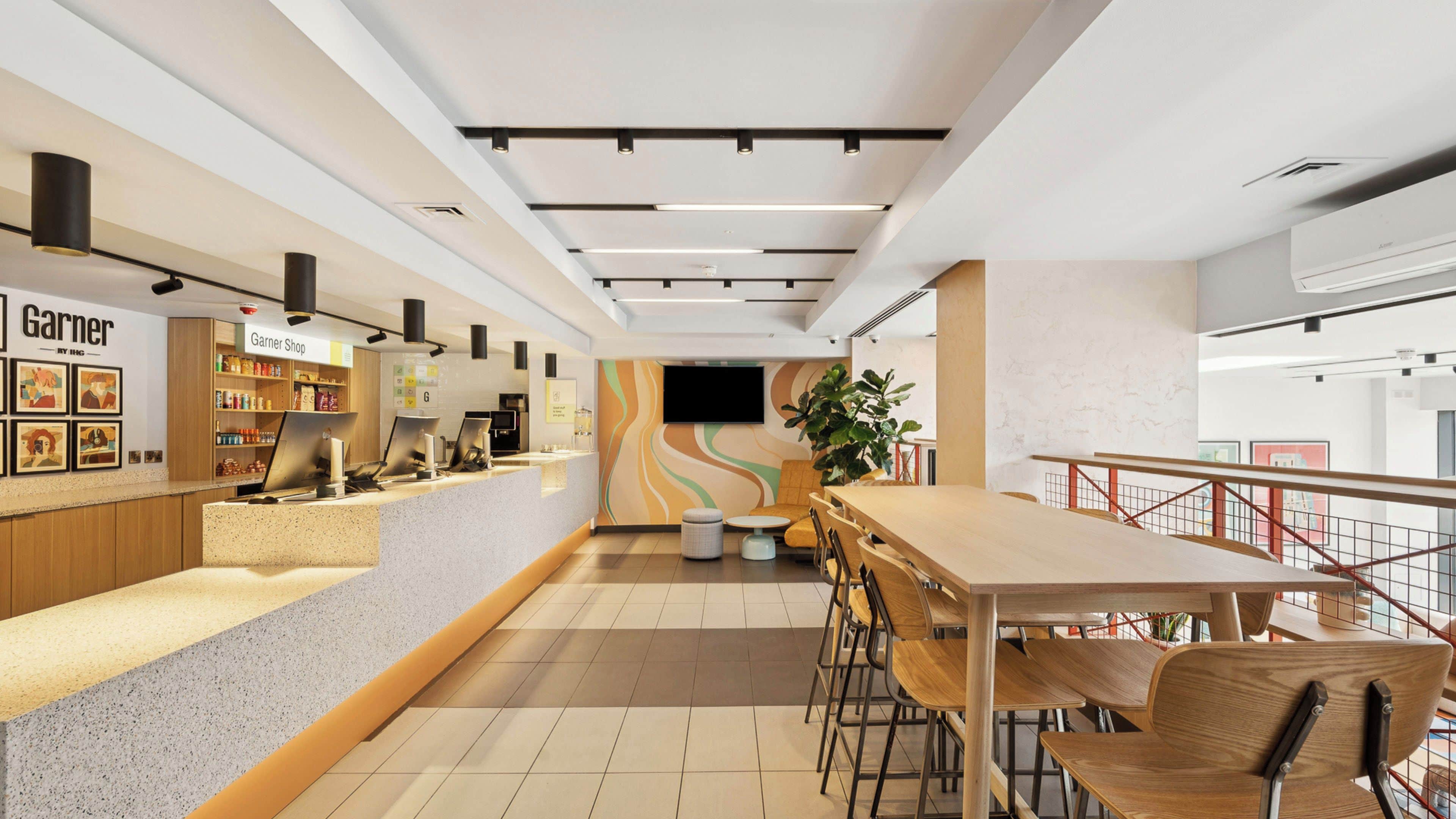 A modern interior with a counter, seating area, and a staircase.