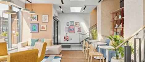 A modern interior with a sofa, chairs, a dining area, and a staircase.
