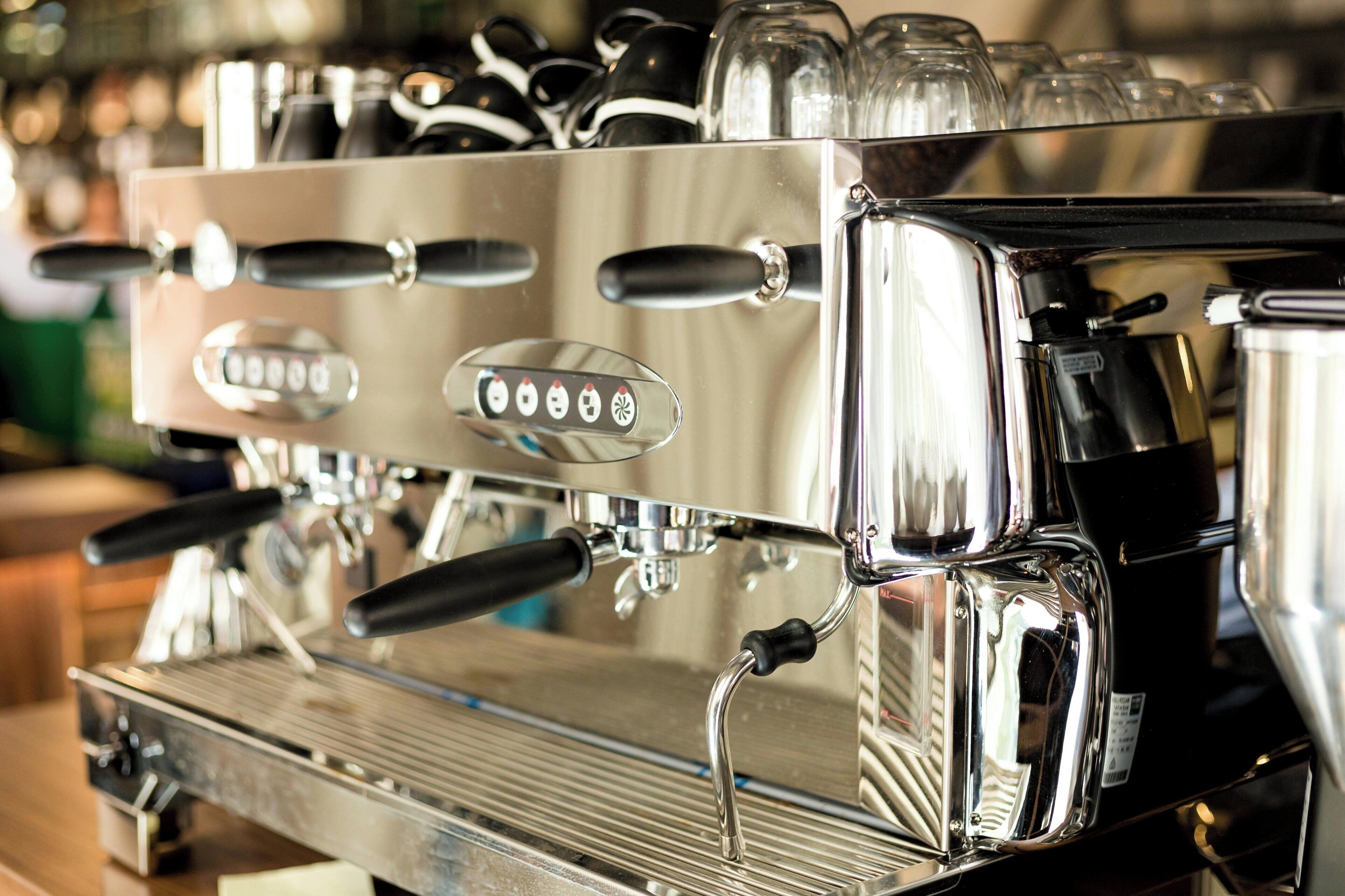 En kommerciel espressomaskine med flere kaffedispensere og en metal bordplade.