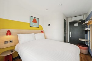 Een hotelkamer met een bed, nachtkastje en een kunstwerk aan de muur.