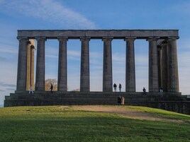 A large classical building with multiple columns and a flat roof.