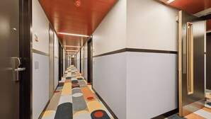A hotel corridor with a patterned carpet, doors on both sides, and a ceiling with recessed lighting. - Garner Edinburgh Haymarket by IHG (Edinburgh)