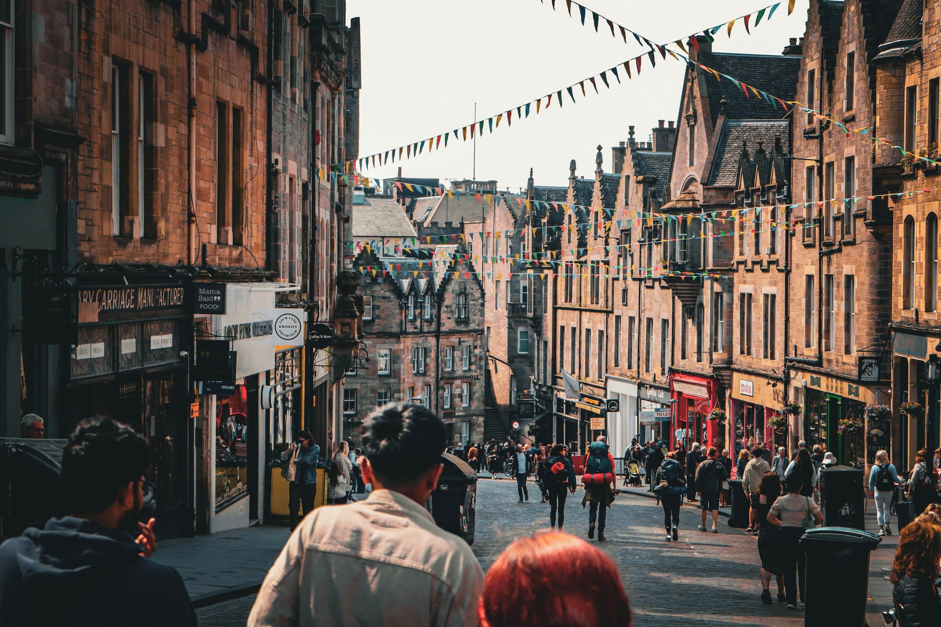 A bustling street with historic buildings, a variety of shops, and people walking.