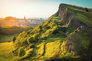 A hill with a path leading to a town with buildings and a church.