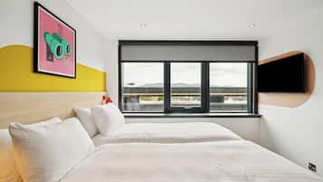 Ein modernes Hotelzimmer mit einem großen Bett, einem Fenster mit Blick und einem angebrachten Fernseher.