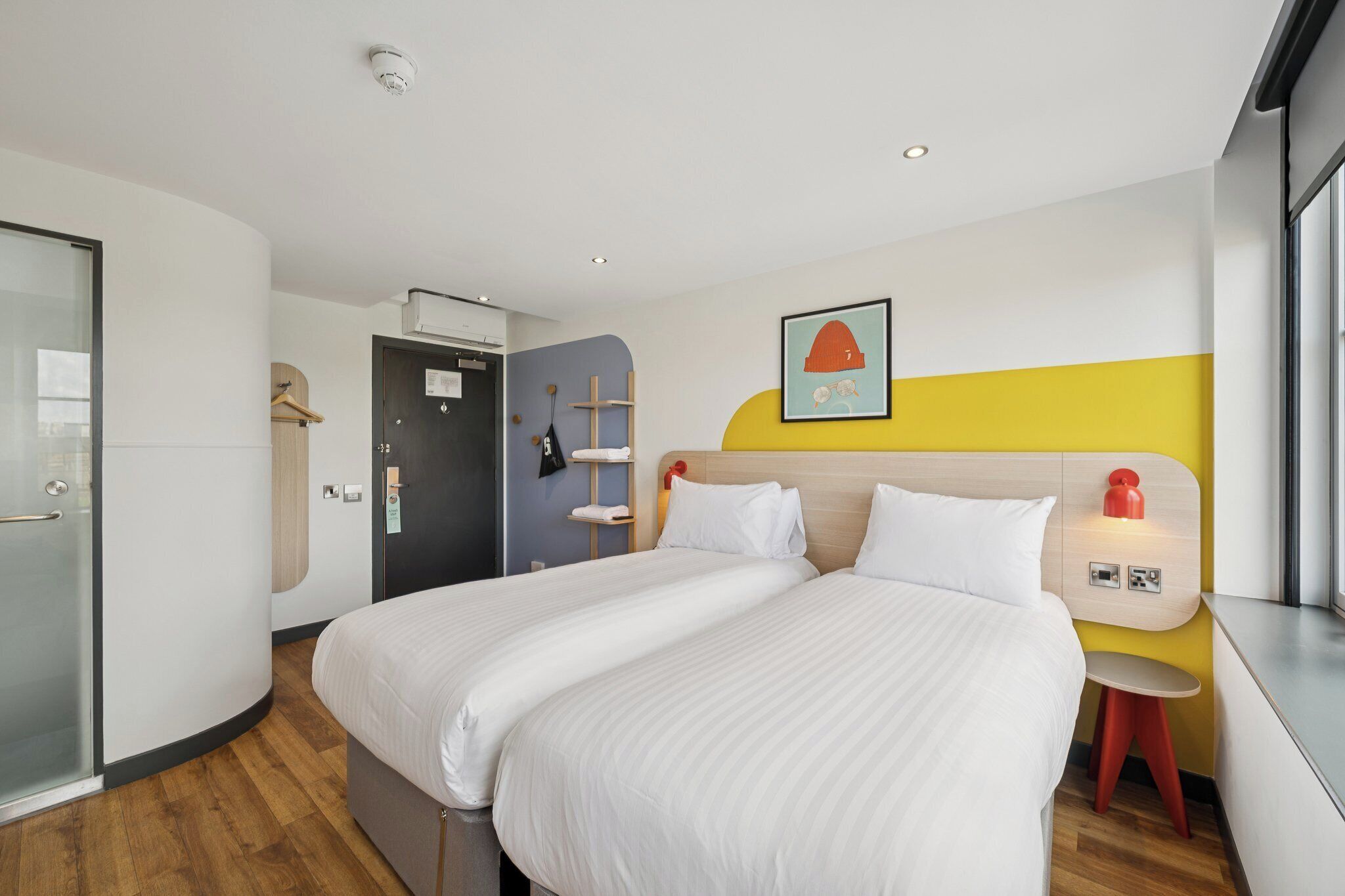 Een hotelkamer met twee bedden, een douche, een kledingkast en een klein tafeltje.