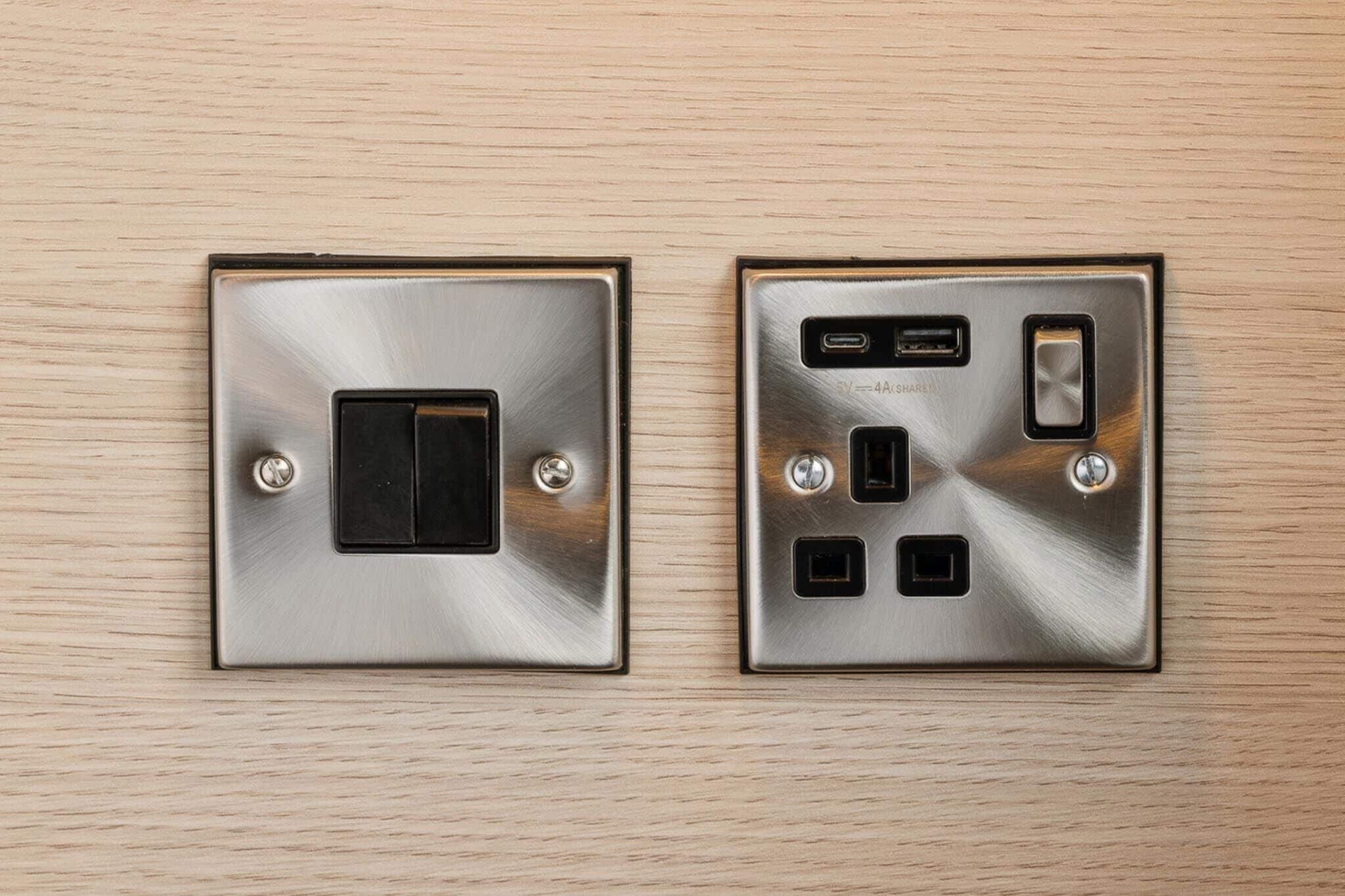 Kaksi seinään kiinnitettävää pistorasiaa, joissa on USB-portit ja virtakytkin.