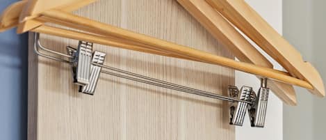 A wooden hanger with metal clips on a wooden surface.