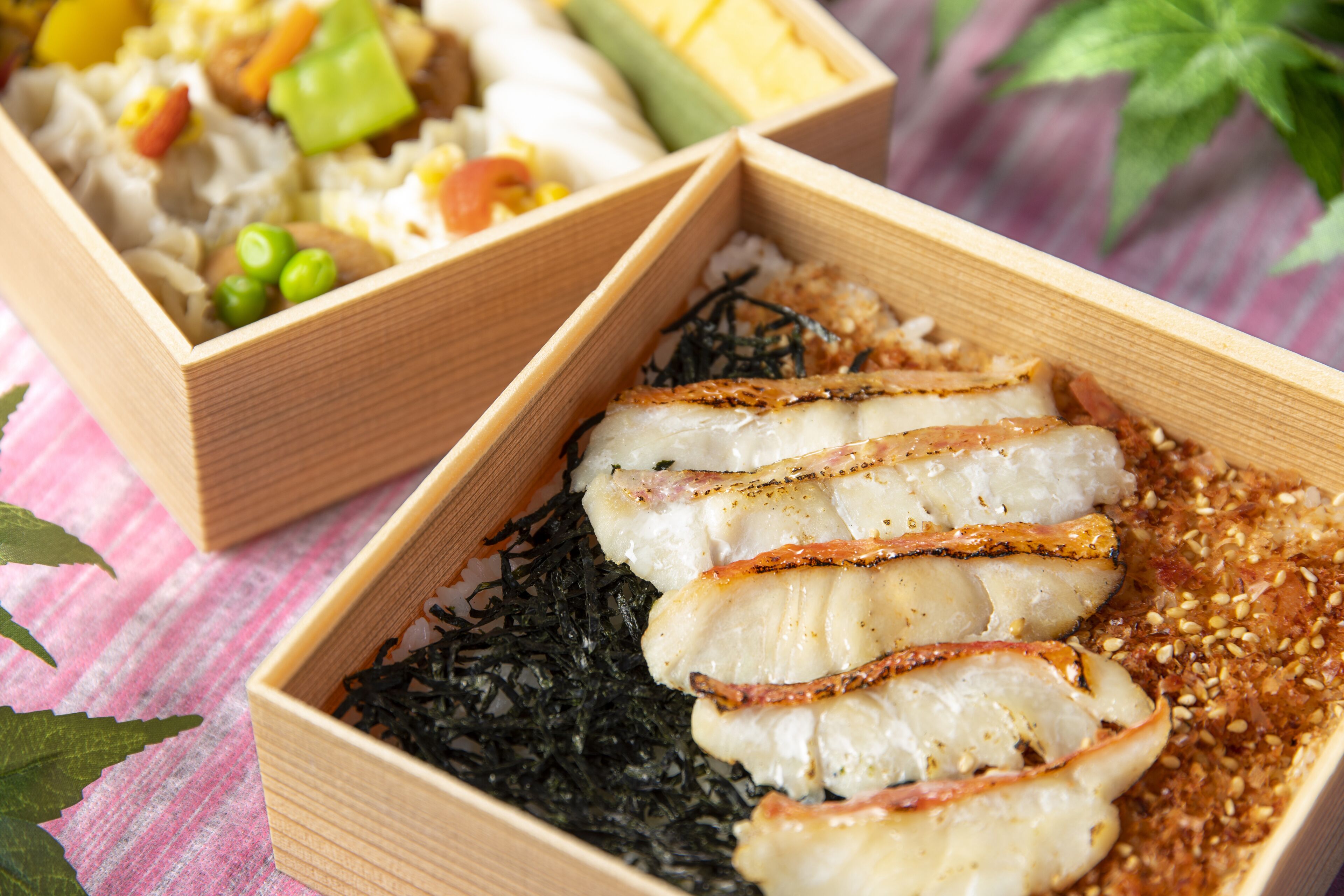 A wooden tray with sliced fish and seaweed, and another tray with vegetables and noodles.