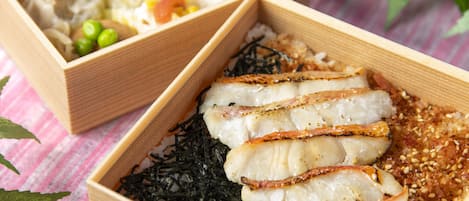 Ein Holztablett mit Fischscheiben und Seetang, sowie ein weiteres Tablett mit Gemüse und Nudeln.