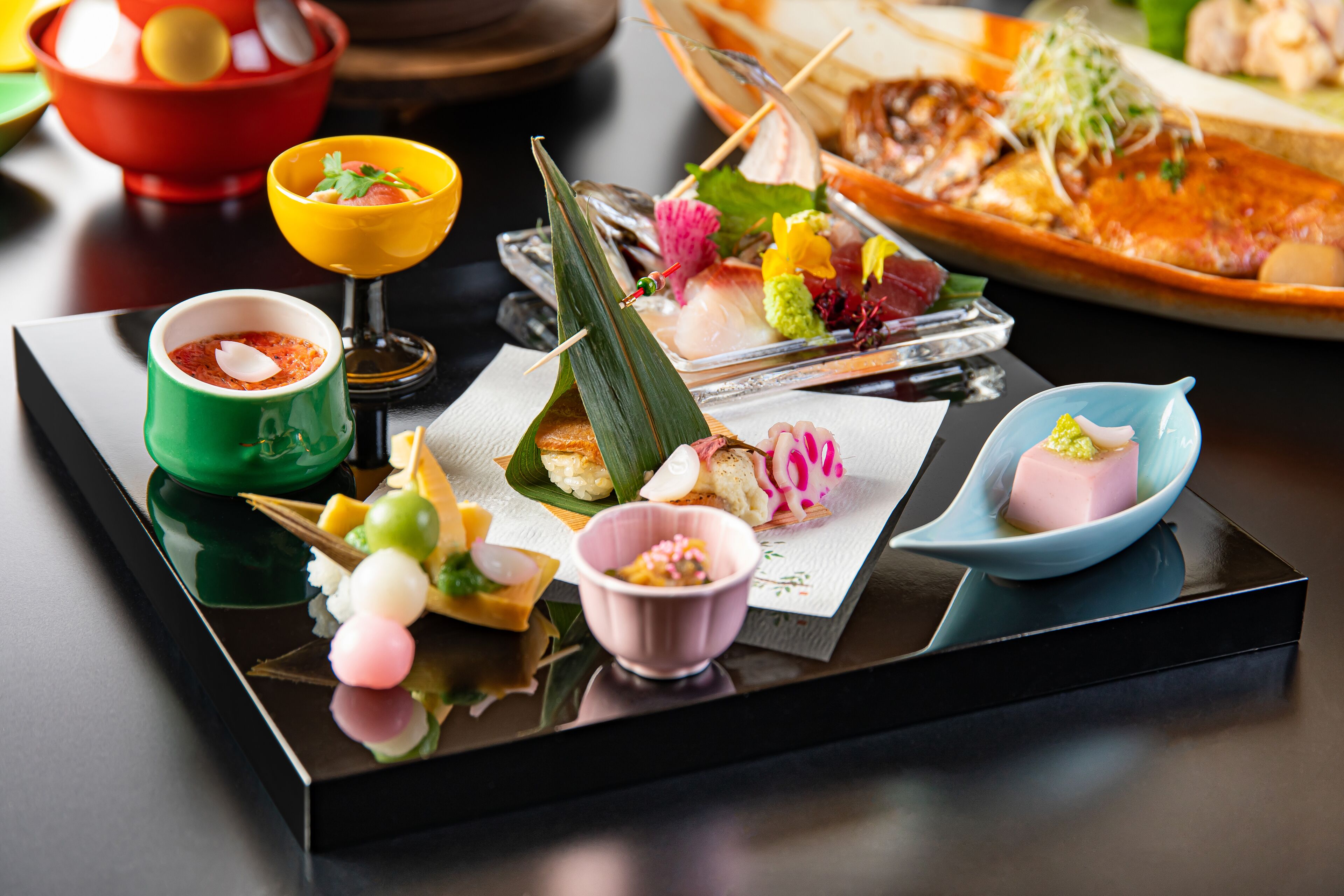 Variedad de platos en una bandeja, incluyendo sushi, sashimi y otras exquisiteces, evocando una experiencia gastronómica japonesa.