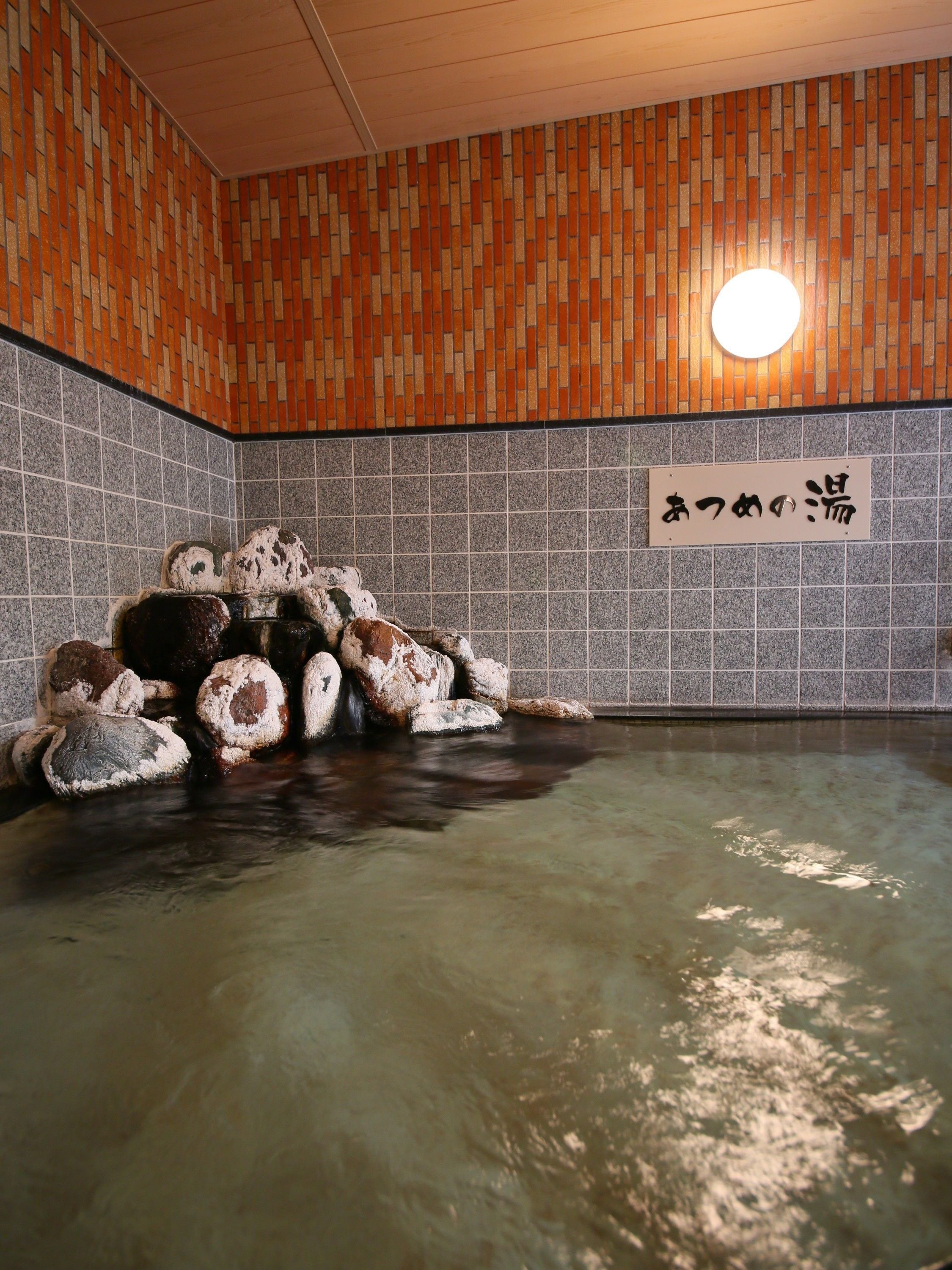 Ett traditionellt japanskt onsen med en vägg täckt av kakel och en skylt på japanska.