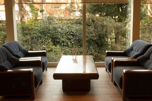 Una habitación con dos sofás orientados hacia una mesa de centro de madera, ventanas amplias con vistas a la vegetación exterior.