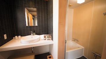 A modern bathroom with a white sink, mirror, and bathtub.