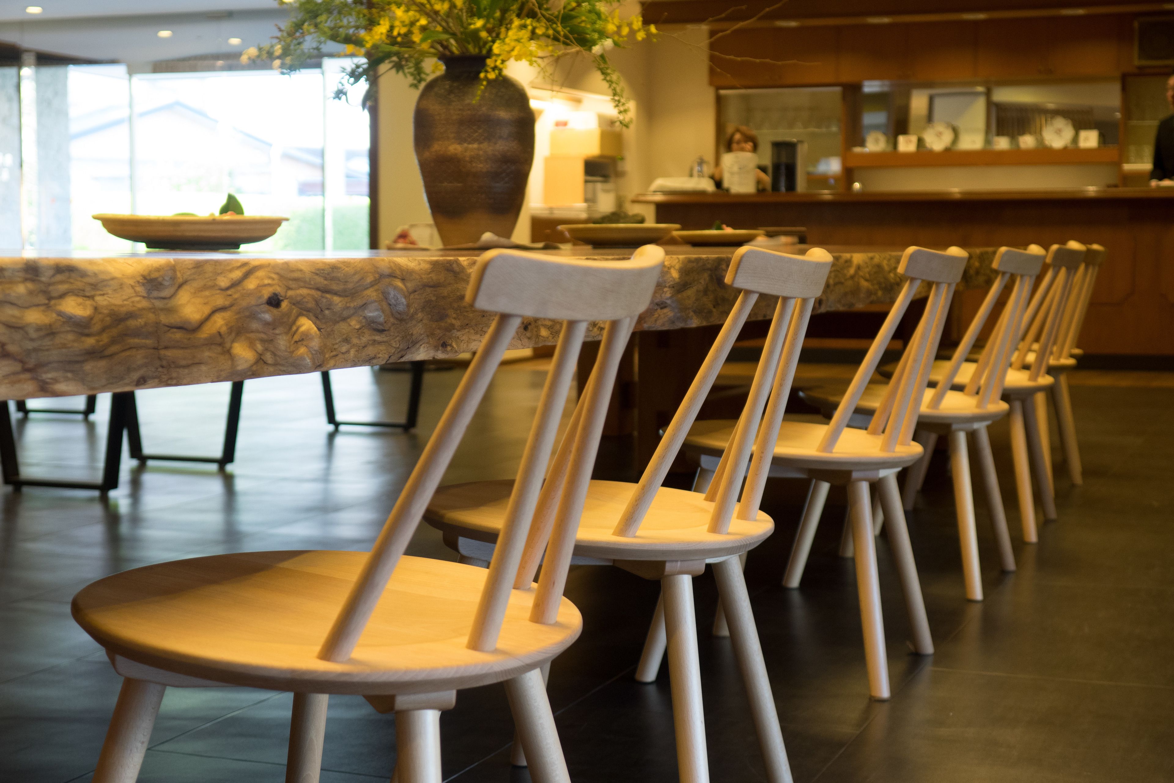Une rangée de chaises en bois et une table en marbre dans un restaurant.