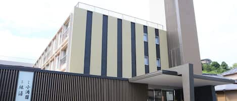 A modern building with a vertical striped facade, a large entrance with a covered walkway, and a sign indicating a business or educational facility.