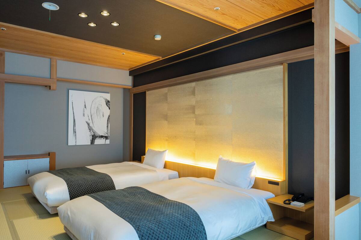 A modern hotel room with two beds, a large window, and a wooden ceiling.