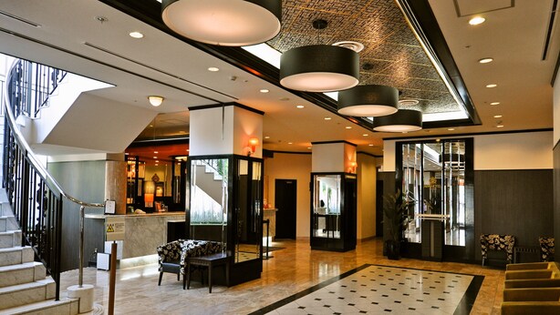 A hotel lobby with a modern design, featuring a staircase, a reception desk, and a seating area. - APA Hotel Obihiro Ekimae (Obihiro)