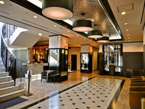 A hotel lobby with a modern design, featuring a staircase, a reception desk, and a seating area. - APA Hotel Obihiro Ekimae (Obihiro)