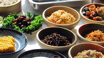 A variety of dishes arranged on a table, including dumplings, scrambled eggs, and different types of salads and side dishes.