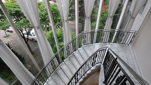 A curved staircase with white steps and black railings, surrounded by white curtains. - APA Hotel Obihiro Ekimae (Obihiro)
