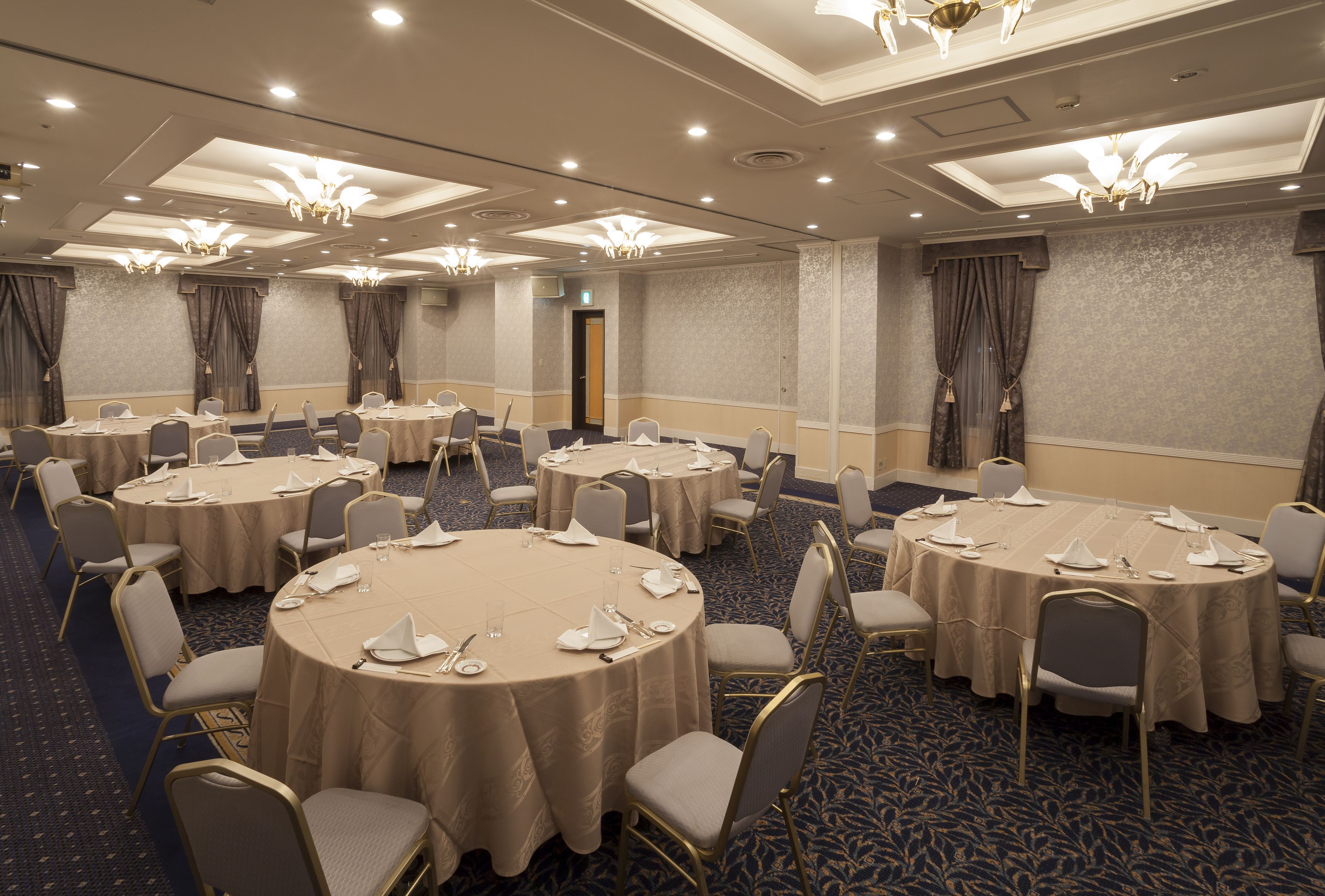 A conference room with multiple round tables, each set with chairs and tableware.