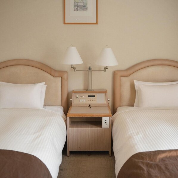 A hotel room with two beds, a bedside table with lamps, and a small table with a radio. - Takarazuka Washington Hotel (Takarazuka)