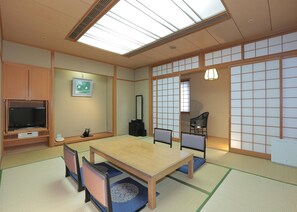 A traditional Japanese-style room with tatami flooring, a low table, and a television on a wooden cabinet. - Takarazuka Washington Hotel (Takarazuka)