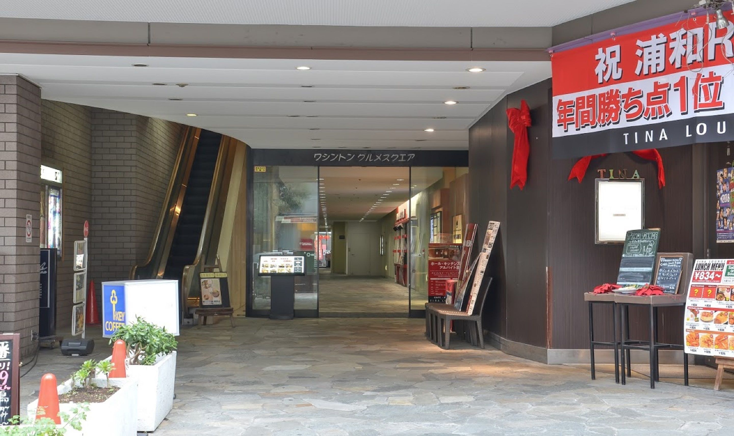 A commercial interior with a TINA LOU sign, a vending machine, and a menu board.