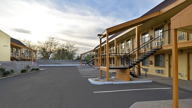 A motel with a central staircase, multiple balconies, and a parking lot. - Rodeway Inn (Sacramento)