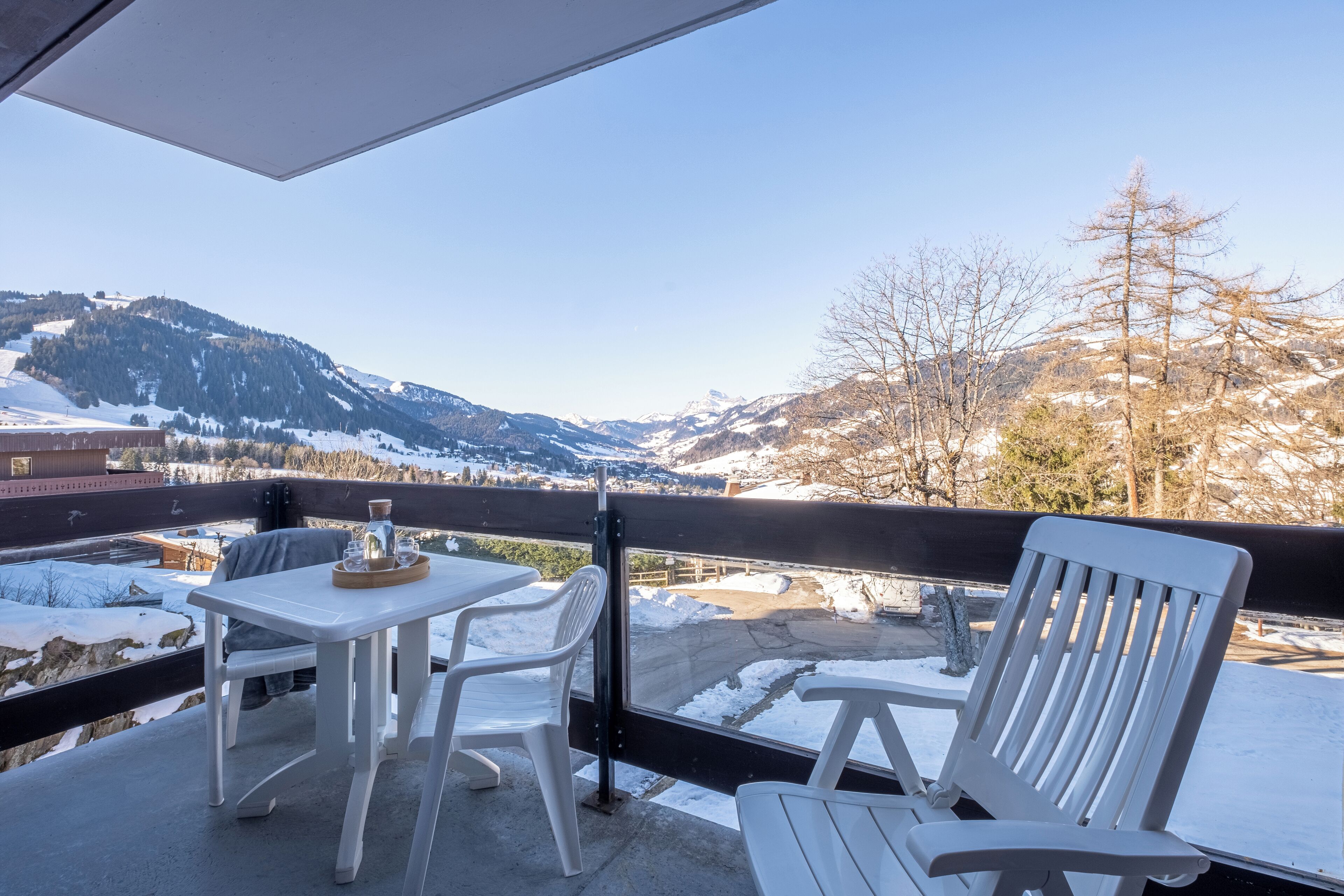 A balcony with a table and chairs, overlooking a snowy mountain landscape.