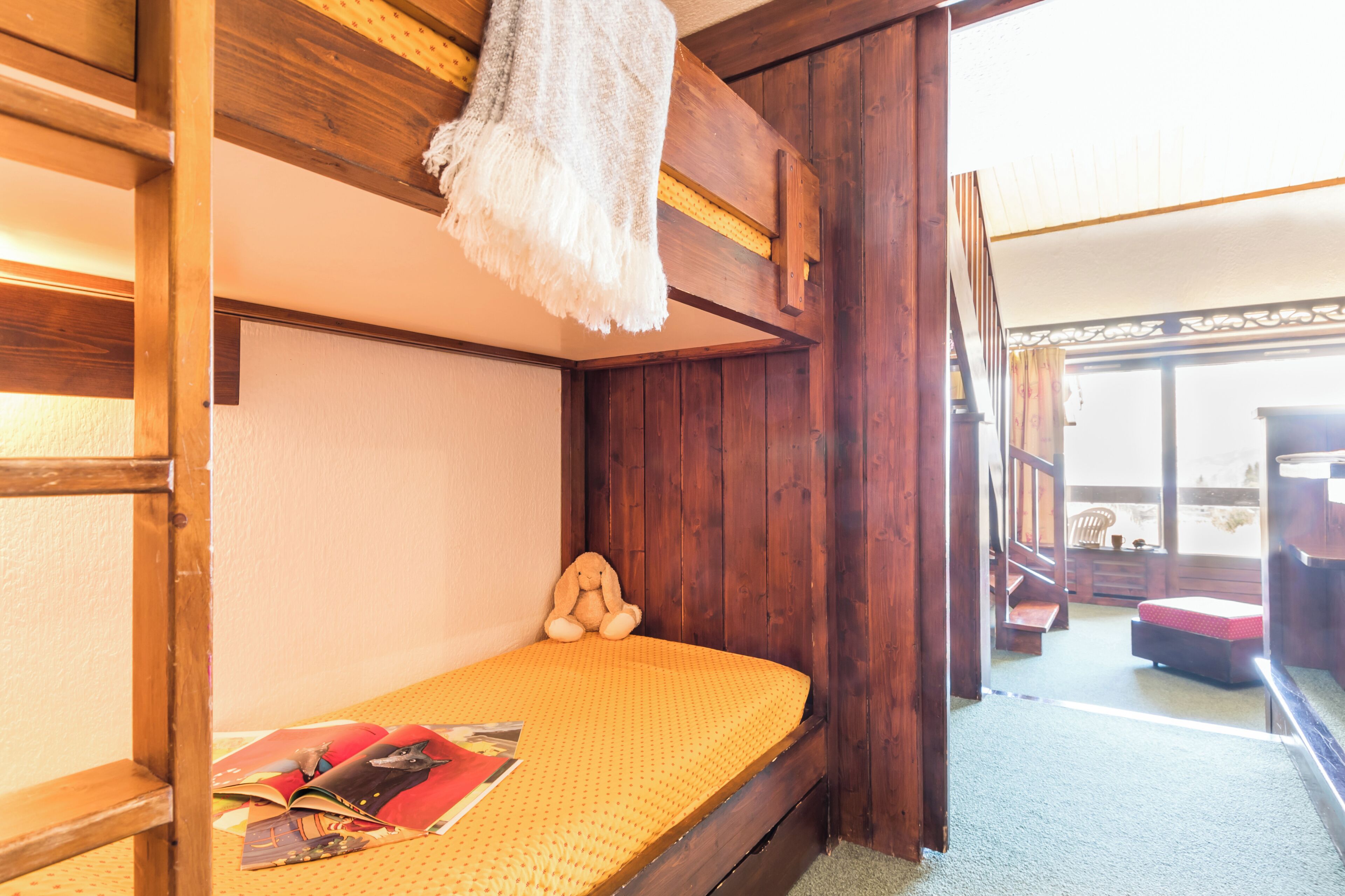 A small, cozy room with a single bed, a wooden headboard, and a hanging light fixture.