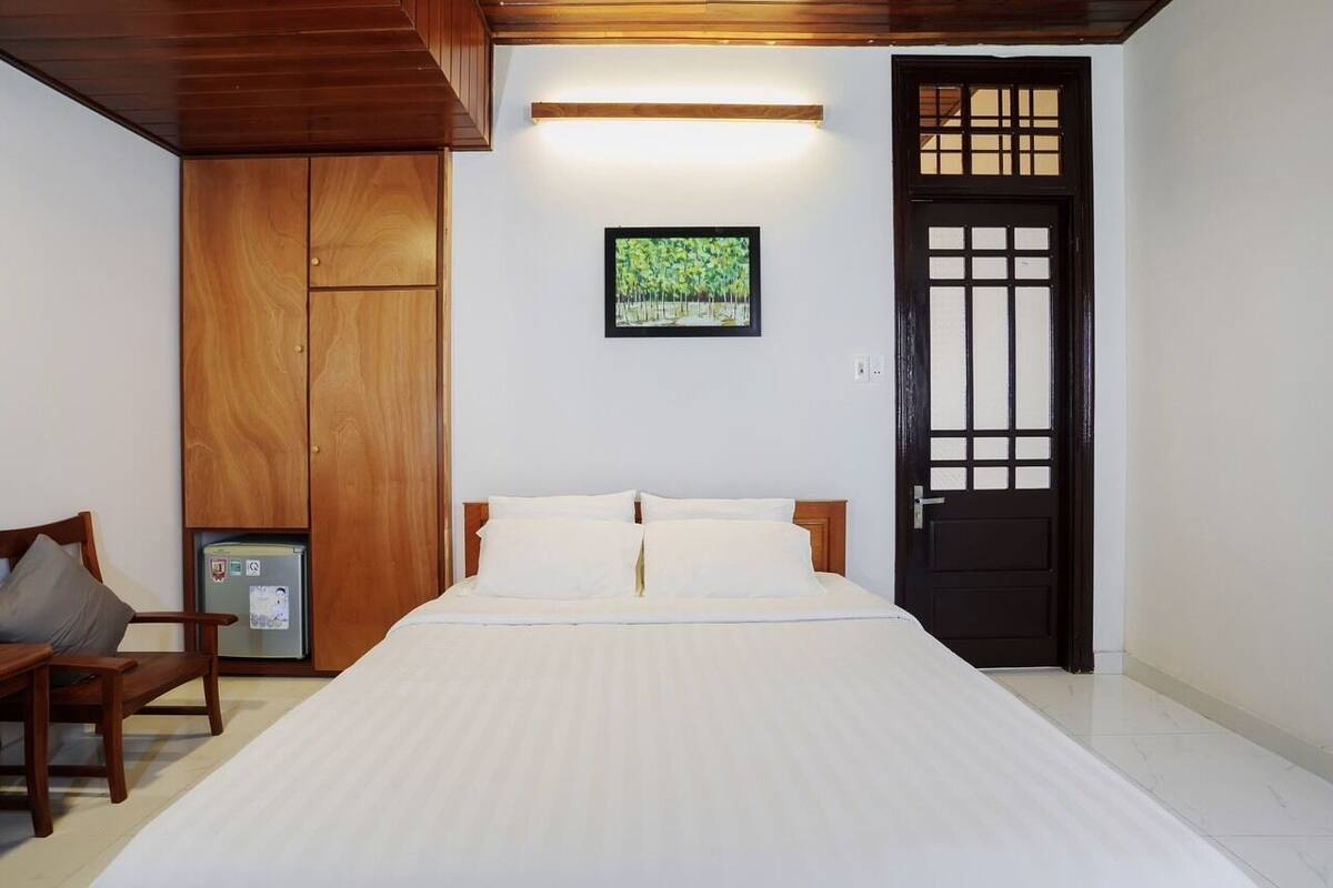 A bedroom with a bed, wooden wardrobe, a small table, and a door with a traditional design.