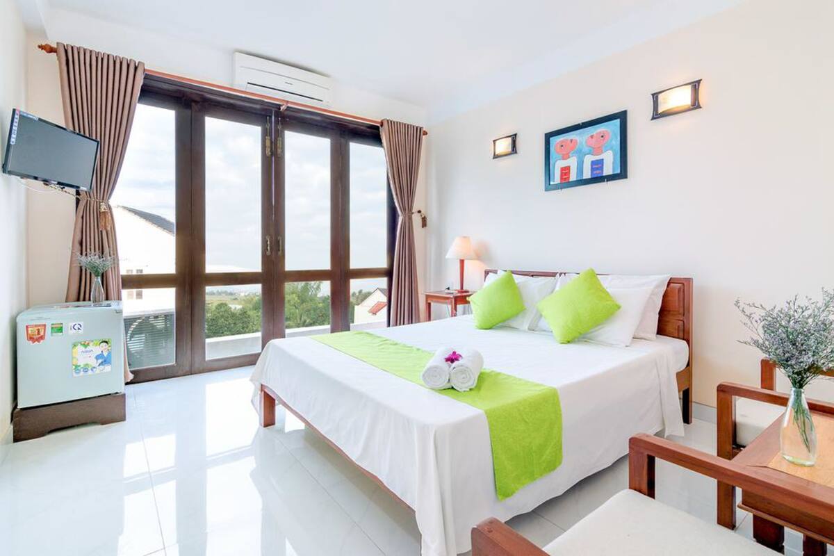 A hotel room with a bed, a desk, a chair, a TV, and a window with curtains.