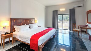 A hotel room with a large bed, a desk, a chair, and a view of the outdoors. - Thansur Sokha Hotel (Kampot)